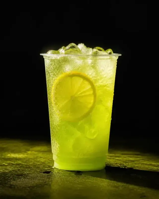 Iced electric-lime loaded tea with citrus and condensation in a clear cup